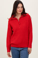 woman wearing a red half-zip sweater with a textured knit and long sleeves paired with blue jeans