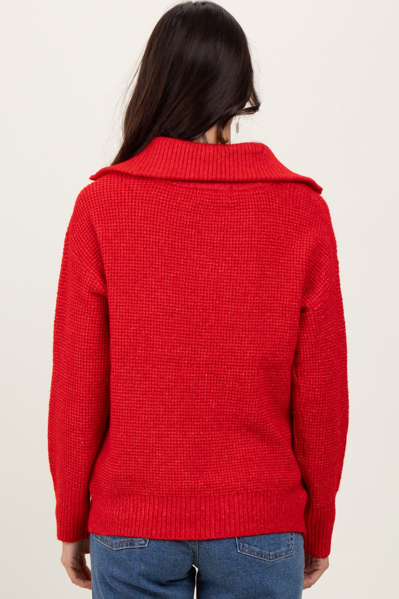 woman wearing a vibrant red chunky knit sweater with a wide collar, viewed from the back