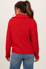 woman wearing a red maternity sweater with a cowl neck, seen from the back, paired with light blue jeans