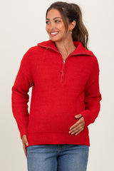 woman wearing a red maternity sweater with a zip collar and holding her baby bump