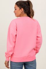 woman wearing a bright pink maternity sweatshirt with a relaxed fit and long sleeves, showing her back