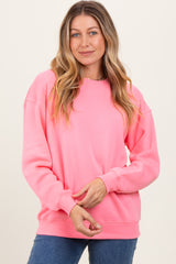 woman wearing a bright pink long sleeve oversized sweatshirt and smiling