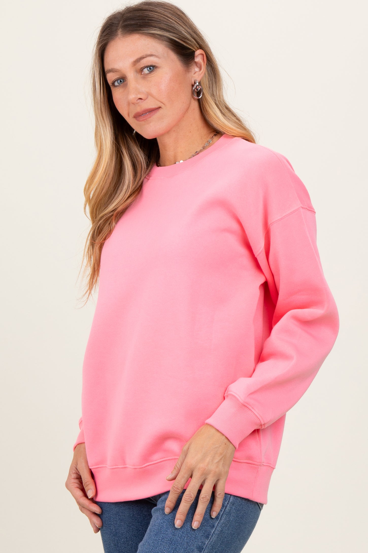 woman wearing a bright pink oversized sweatshirt with long sleeves and a relaxed fit