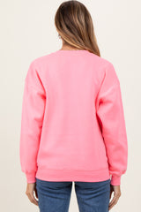woman wearing a bright pink oversized sweatshirt, showcasing a relaxed fit and ribbed cuffs, viewed from the back