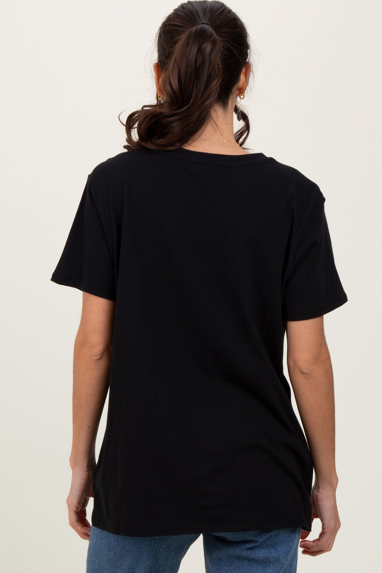 woman wearing a black short sleeve t-shirt, viewed from the back, paired with blue jeans