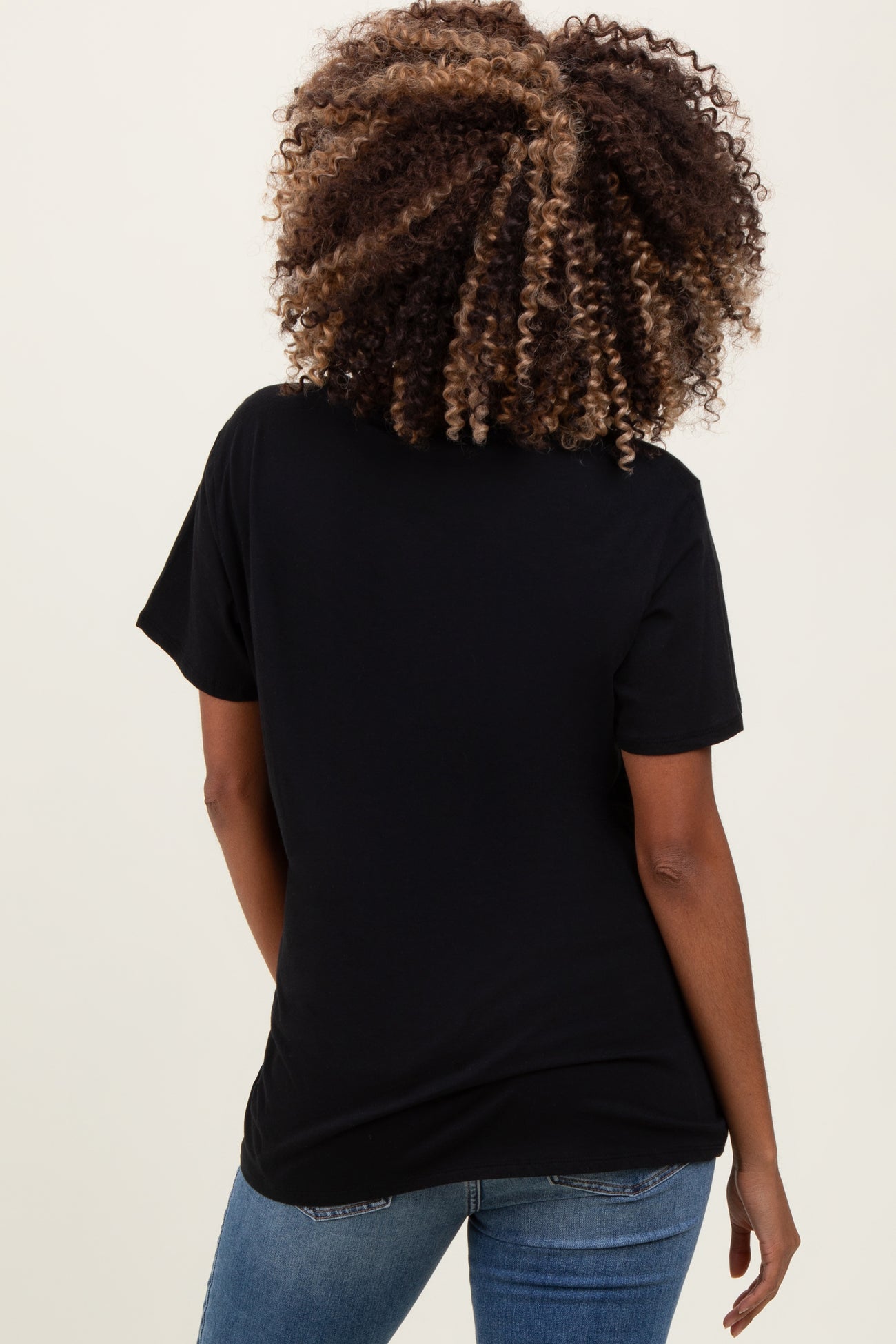woman wearing a black short sleeve maternity top, view from the back, paired with blue jeans