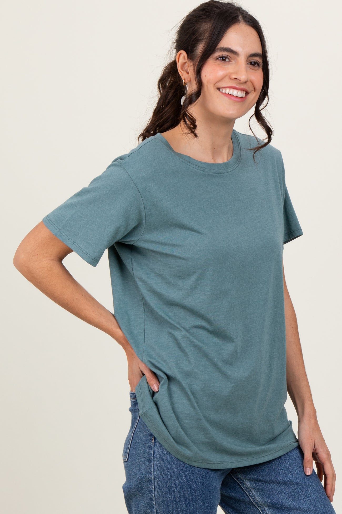 woman wearing a teal short sleeve t-shirt with a relaxed fit and round neckline, smiling while standing sideways