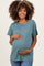woman wearing a teal maternity t-shirt and cradling her baby bump
