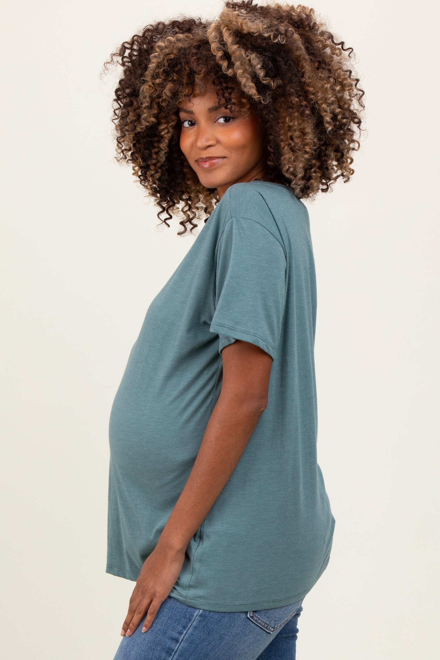 woman wearing a teal short sleeve maternity top and showing her baby bump