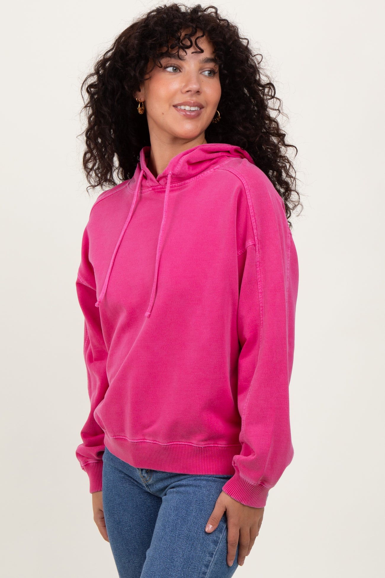 woman wearing a bright pink hooded sweatshirt with a relaxed fit and long sleeves