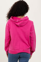 woman wearing a bright pink hoodie with a relaxed fit and a drawstring hood, viewed from the back
