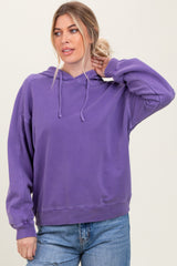 woman wearing a purple oversized hoodie with a front pocket and drawstring hood, paired with light blue jeans