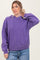woman wearing a purple oversized hoodie with a front pocket and drawstring hood, paired with light blue jeans