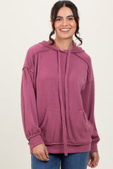 woman wearing a rose pink oversized hooded sweater with ribbed texture and front pockets