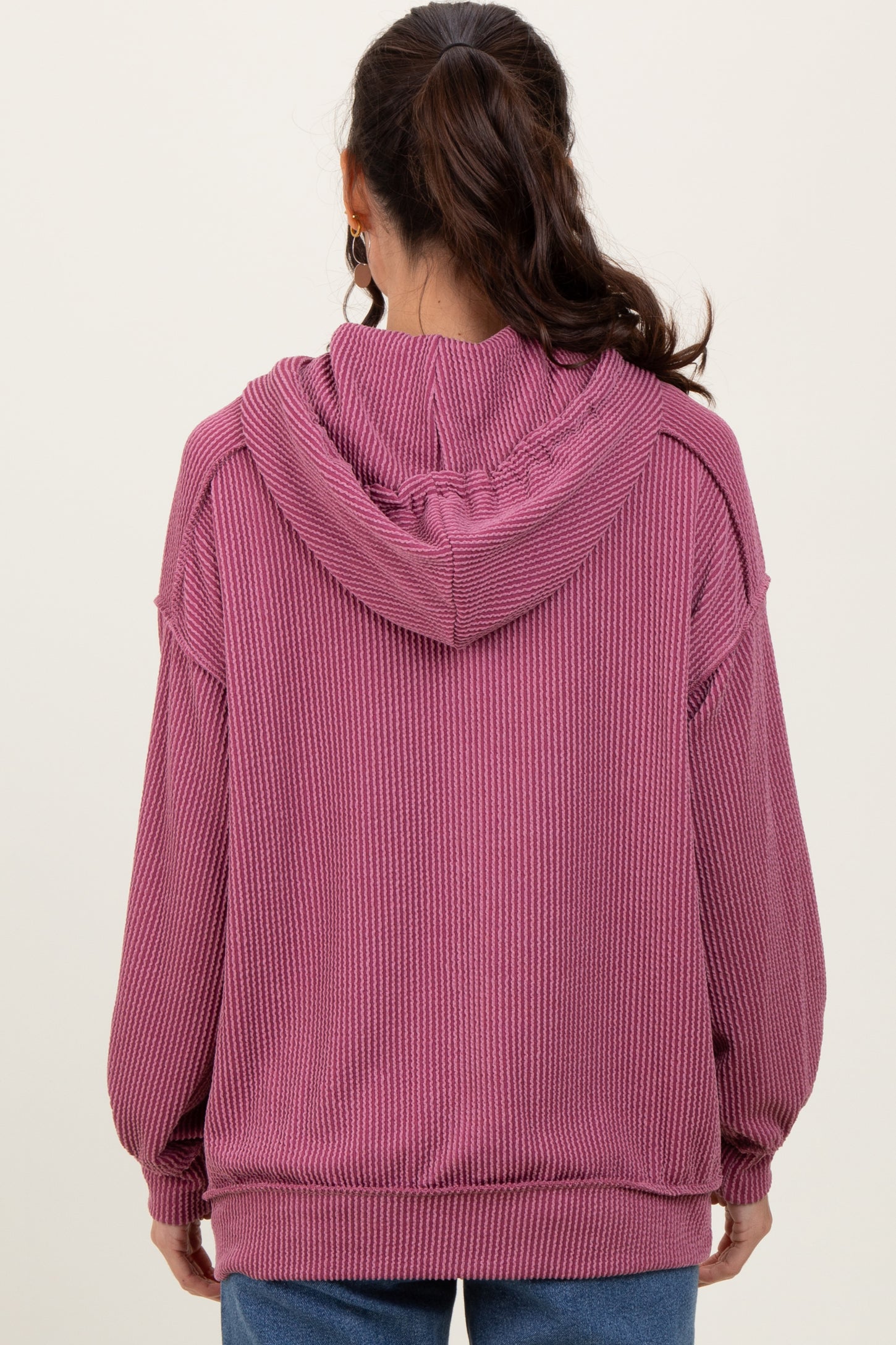 woman wearing a cozy mauve oversized hooded sweatshirt with ribbed texture viewed from the back