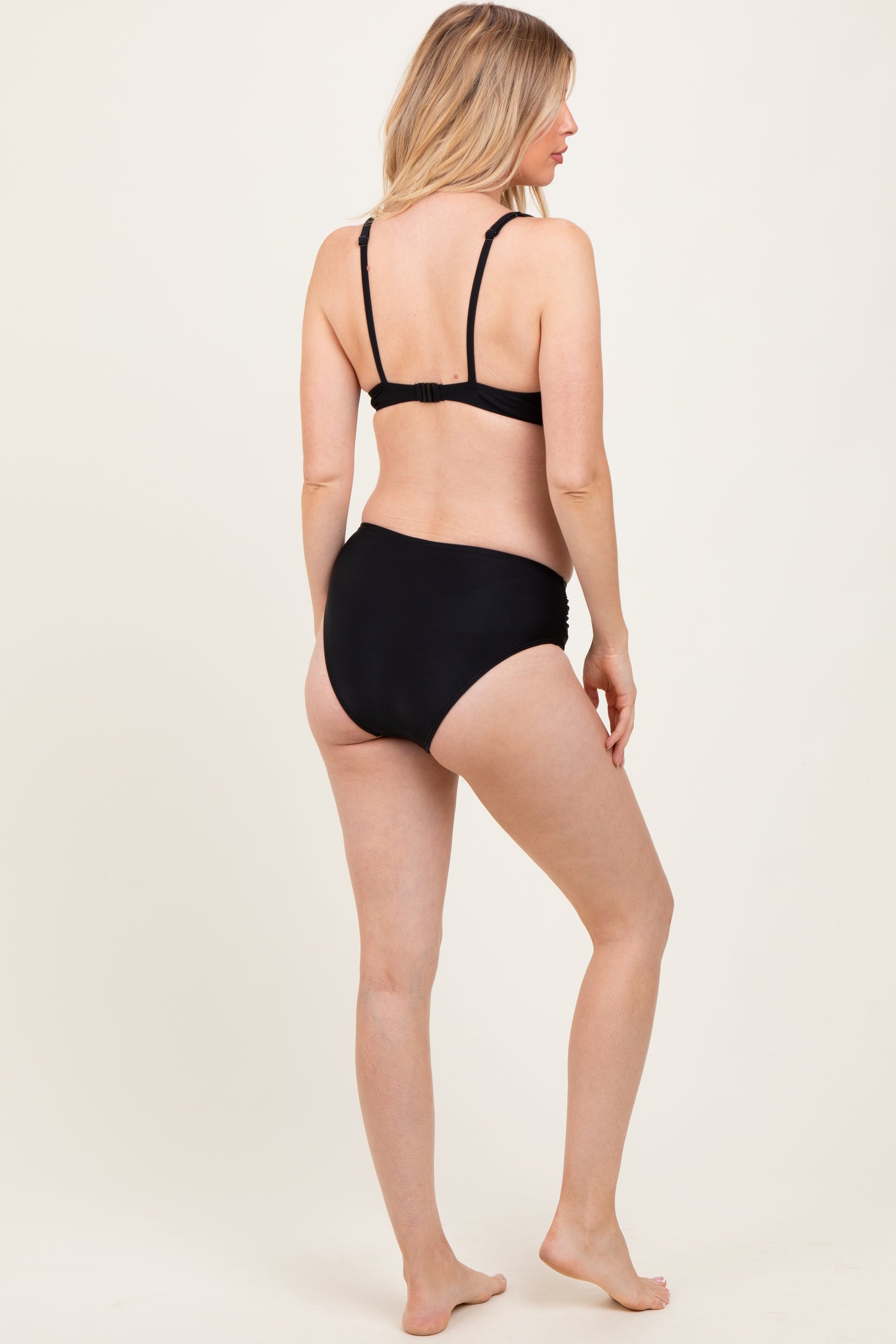woman wearing a black maternity bikini from the back, showing a fitted top and high-waisted bottoms