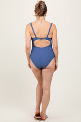woman wearing a blue ribbed maternity swimsuit with a cutout back design, showing no visible baby bump