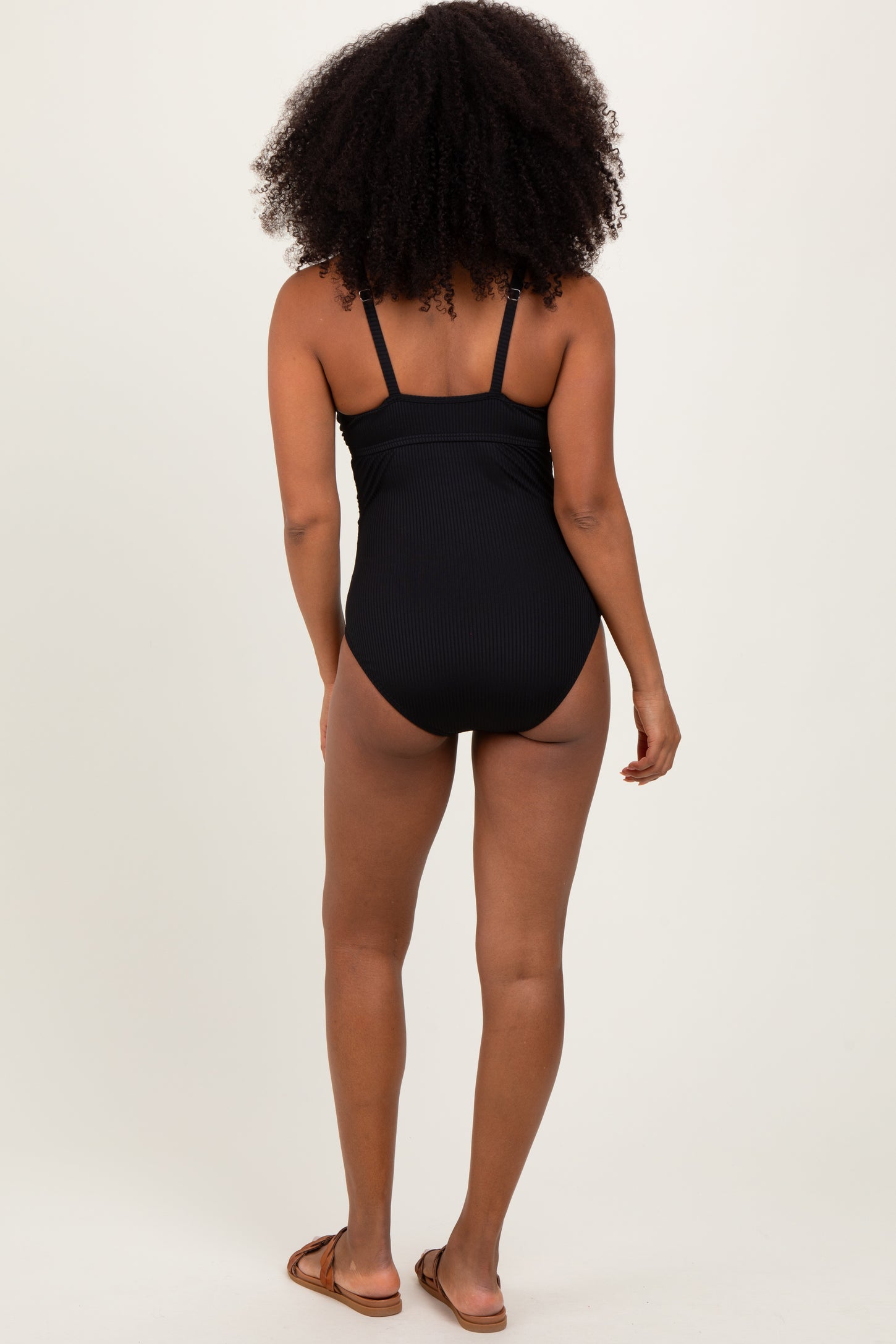 woman wearing a black ribbed one-piece swimsuit, viewed from the back
