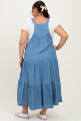 woman wearing a light blue denim maxi dress with tiered ruffles and adjustable straps, seen from the back