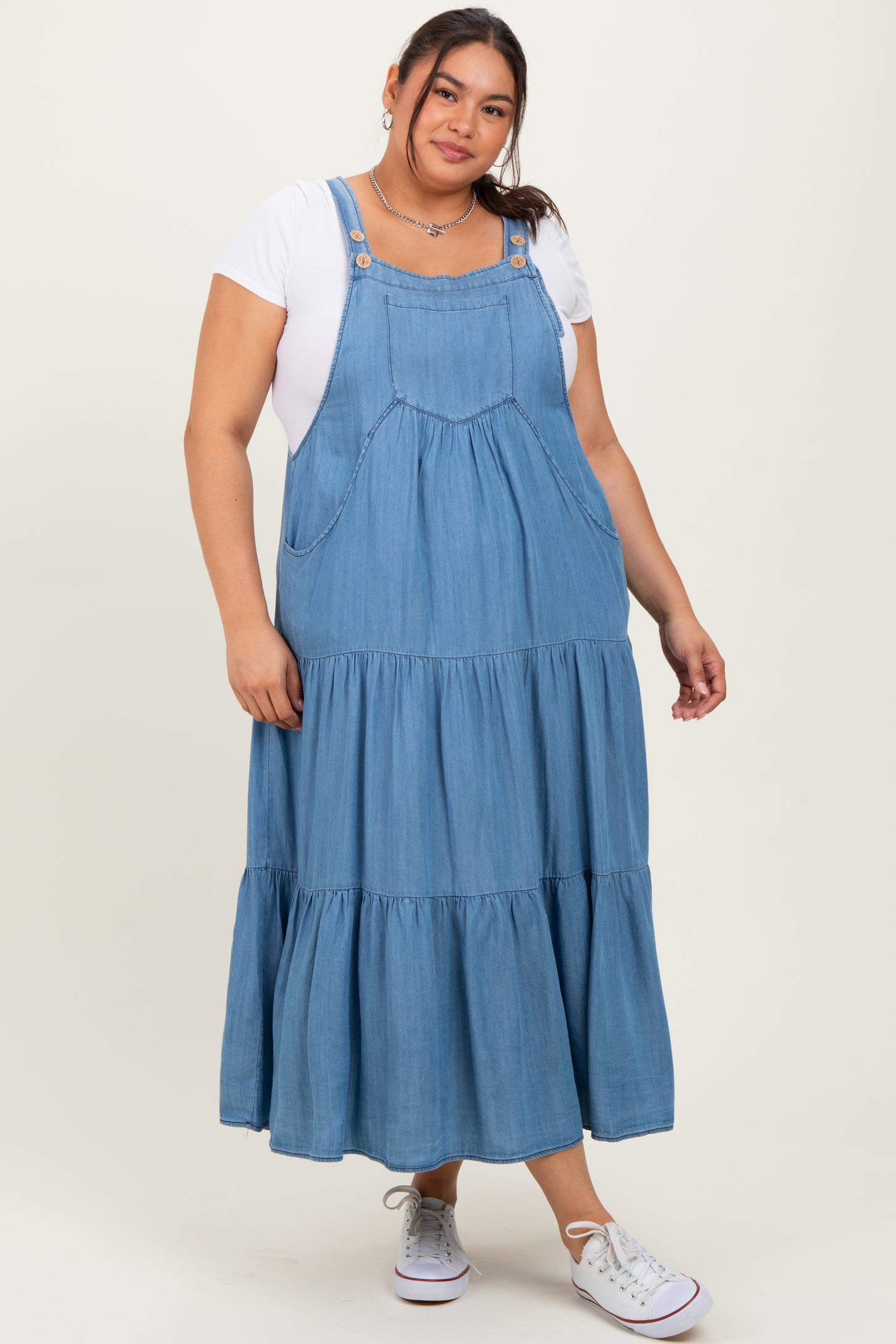 woman wearing a blue denim maxi dress with tiered ruffles over a white t-shirt and white sneakers