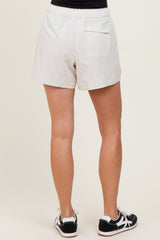 woman wearing cream-colored short shorts with an elastic waistband and a back pocket, viewed from the back