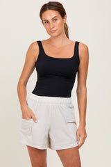 woman wearing a black fitted tank top and light beige athletic shorts with side pockets