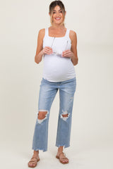 woman wearing a white tank top and distressed light blue maternity jeans, holding sunglasses and showing her baby bump