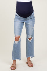woman wearing distressed light blue maternity jeans with a dark blue over-the-bump panel and open-toe sandals