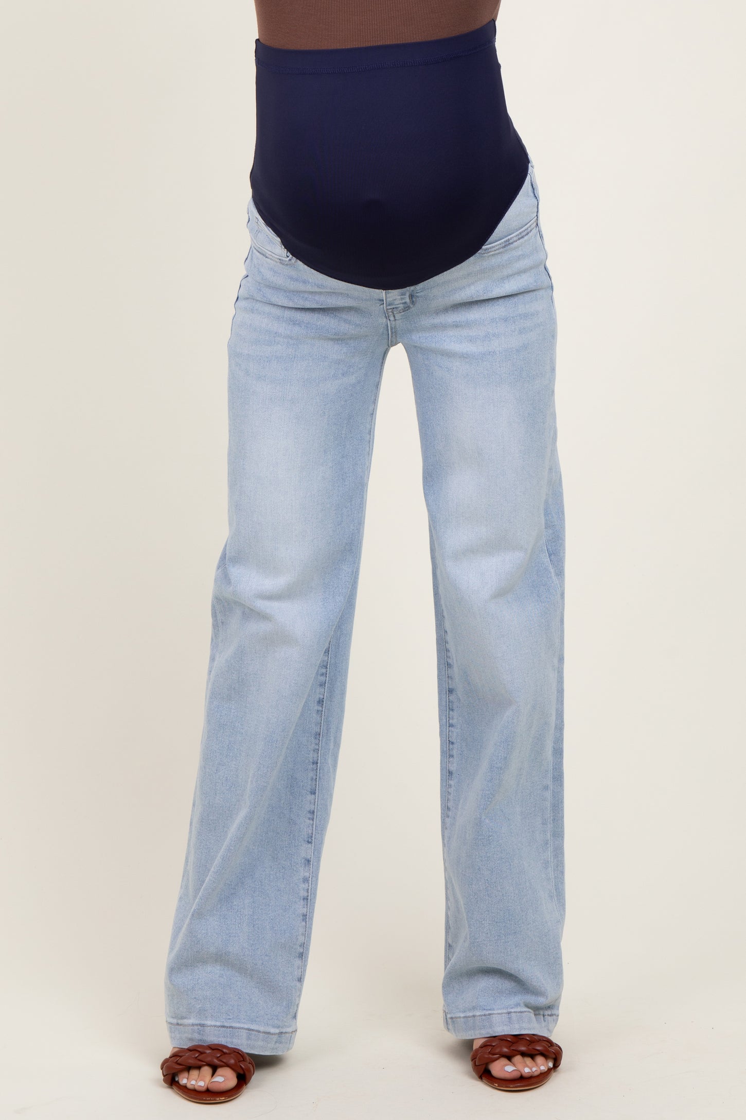 woman wearing light blue maternity jeans with a navy blue supportive waistband and tan sandals