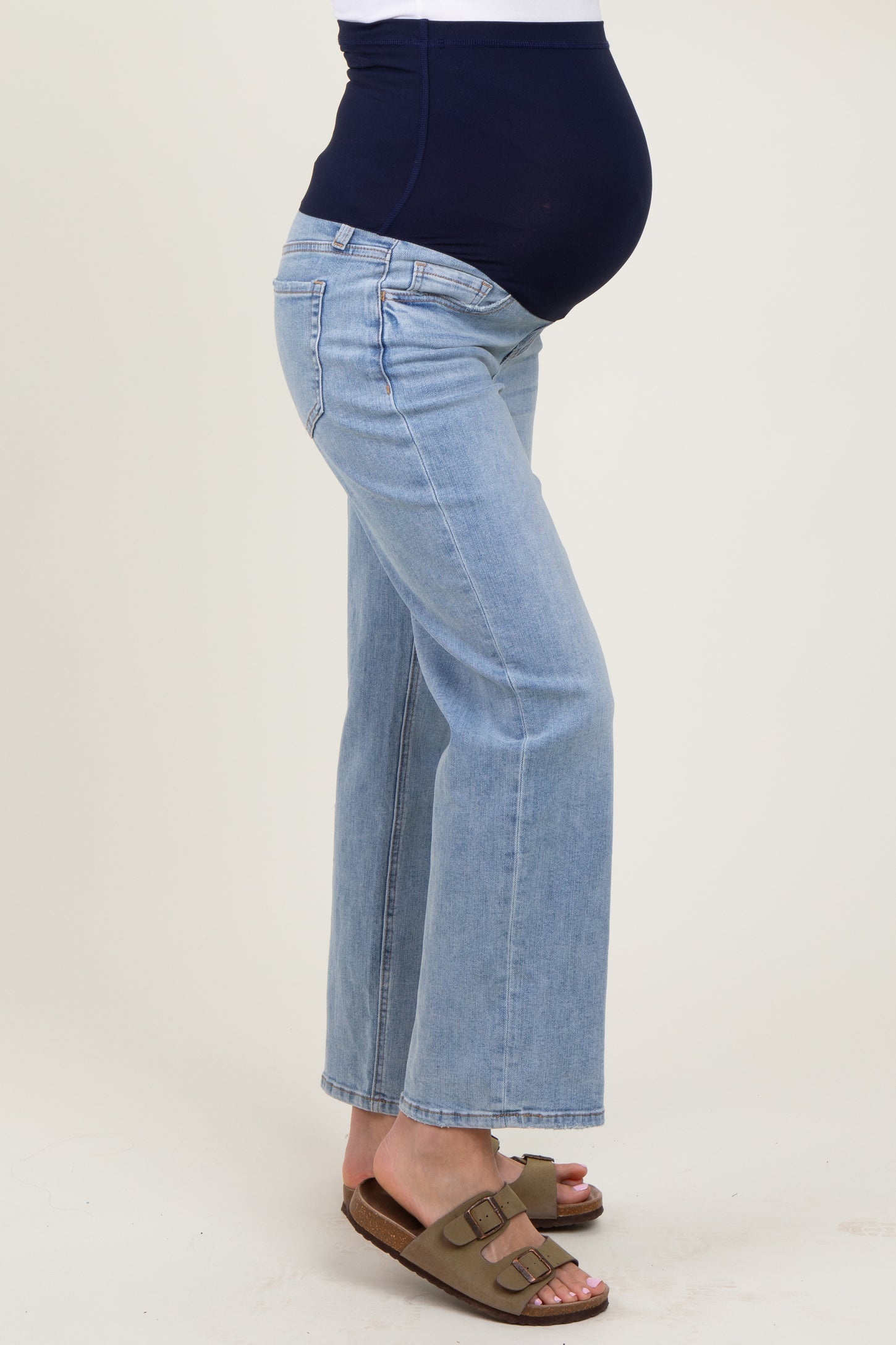 woman wearing light blue maternity flared jeans with a navy blue supportive waistband and visible baby bump
