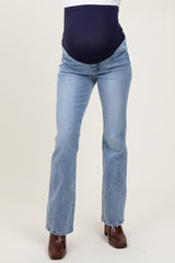 woman wearing light blue maternity flared jeans with a dark blue over-the-bump panel and brown heeled boots
