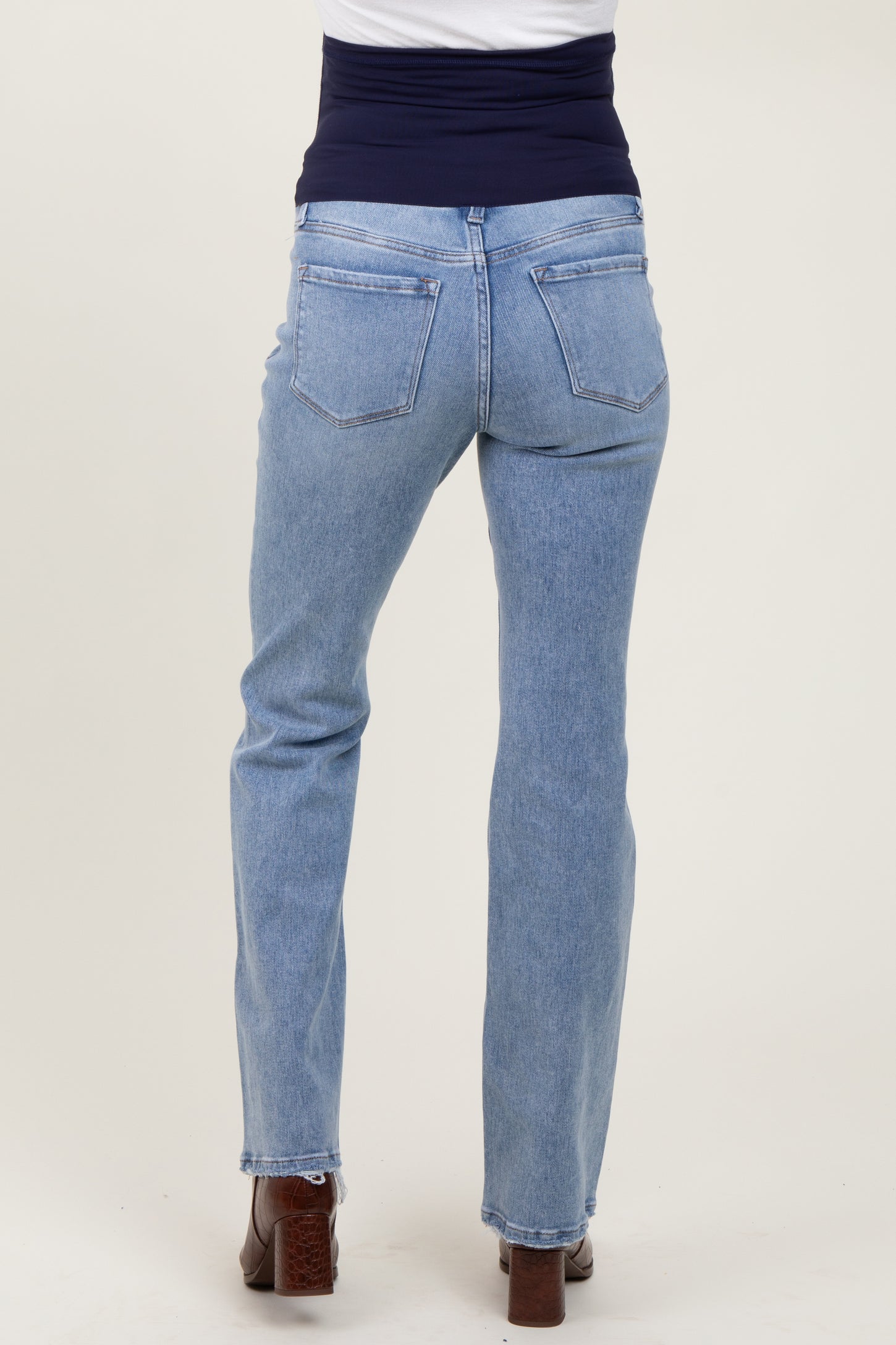 woman wearing light blue maternity jeans with a supportive belly band, showing the back view of the jeans