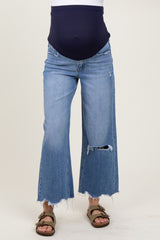woman wearing a navy blue maternity top with a baby bump and distressed wide-leg denim jeans
