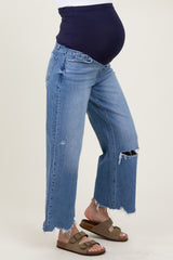 woman wearing light blue distressed maternity jeans with a navy blue over-the-bump panel and revealing her baby bump