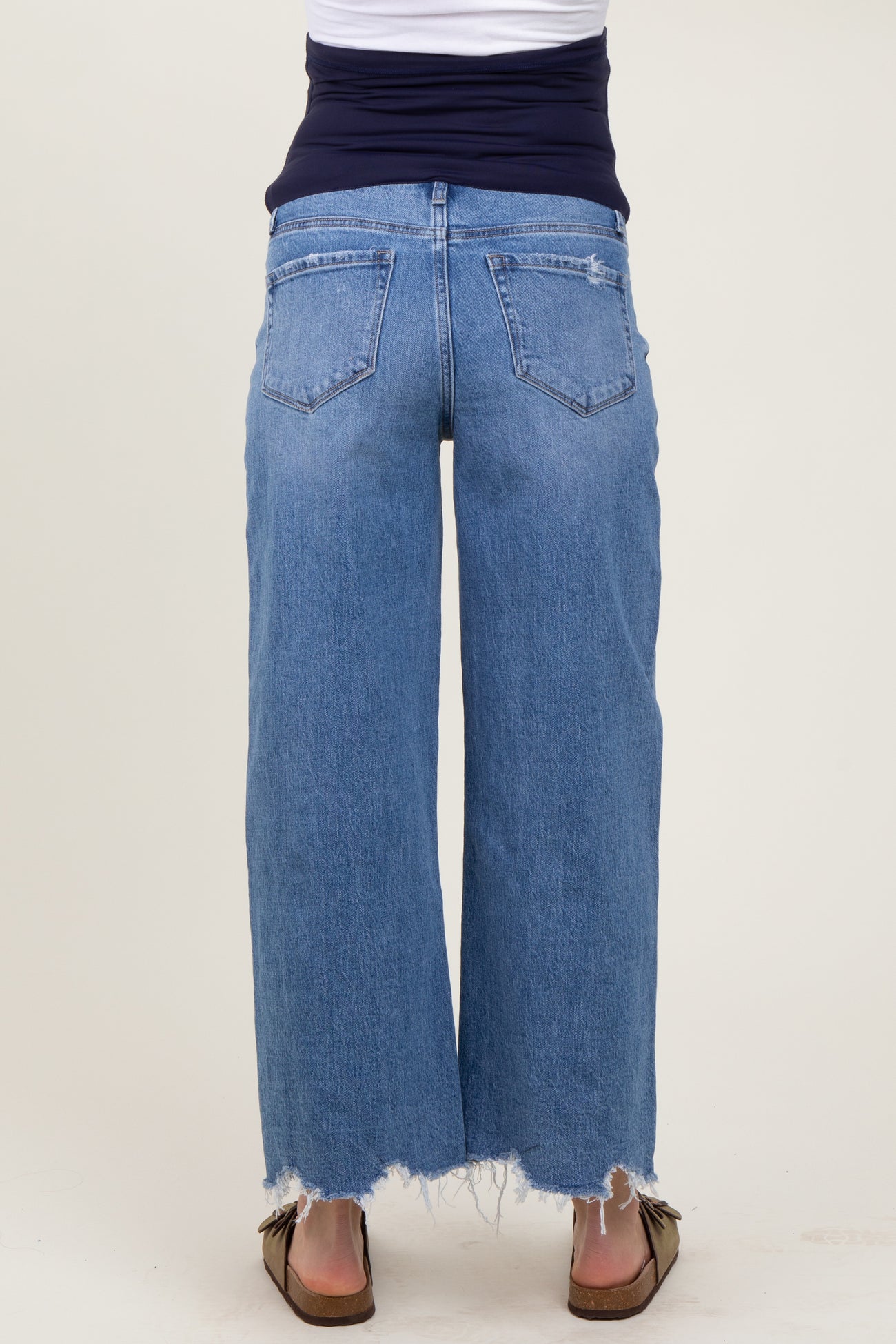 woman wearing light blue wide-leg maternity jeans with a distressed hem and a navy blue top