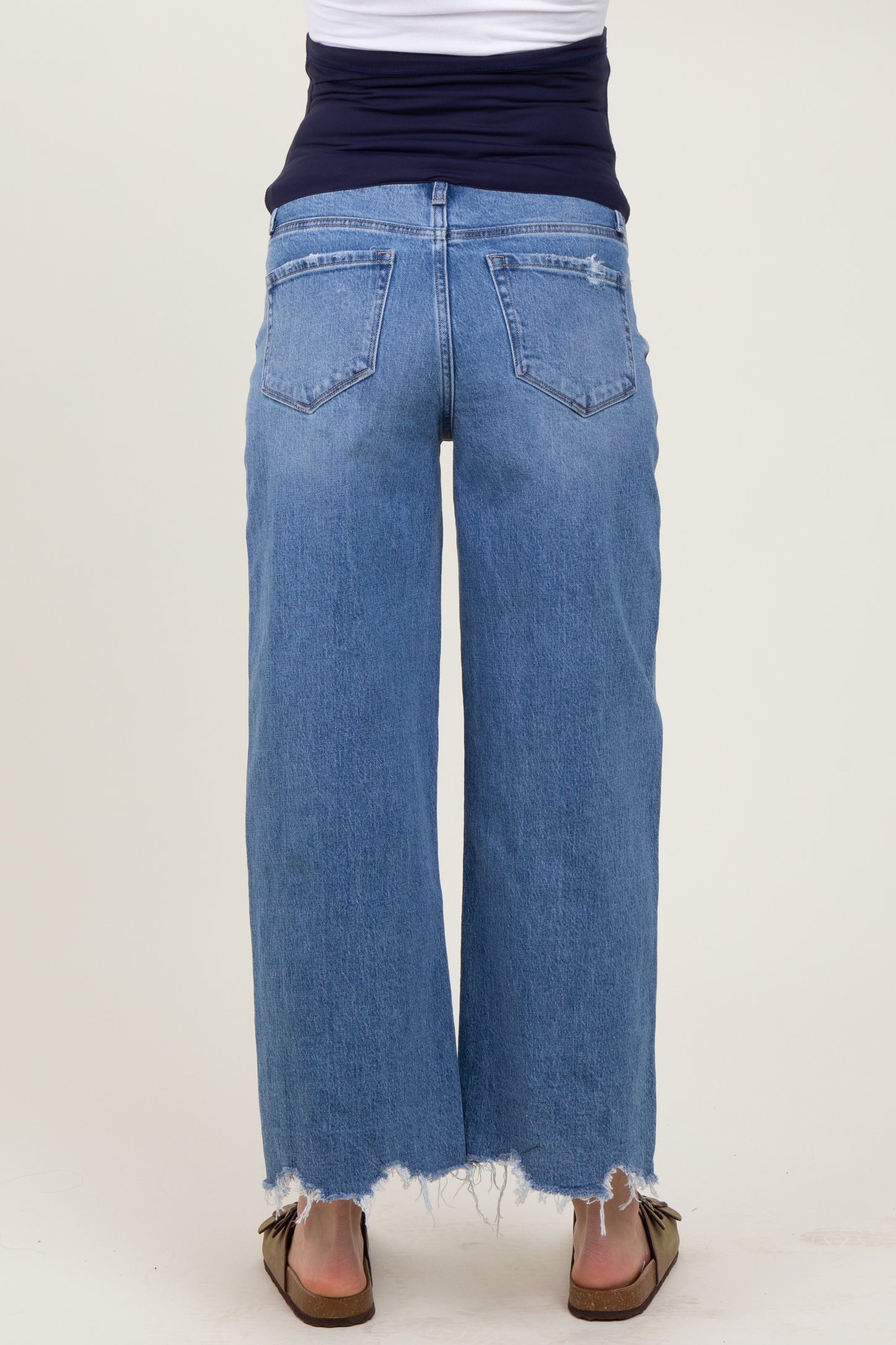 woman wearing light blue wide-leg maternity jeans with a distressed hem and a navy blue top