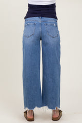 woman wearing light blue wide-leg maternity jeans with a distressed hem and a navy blue top