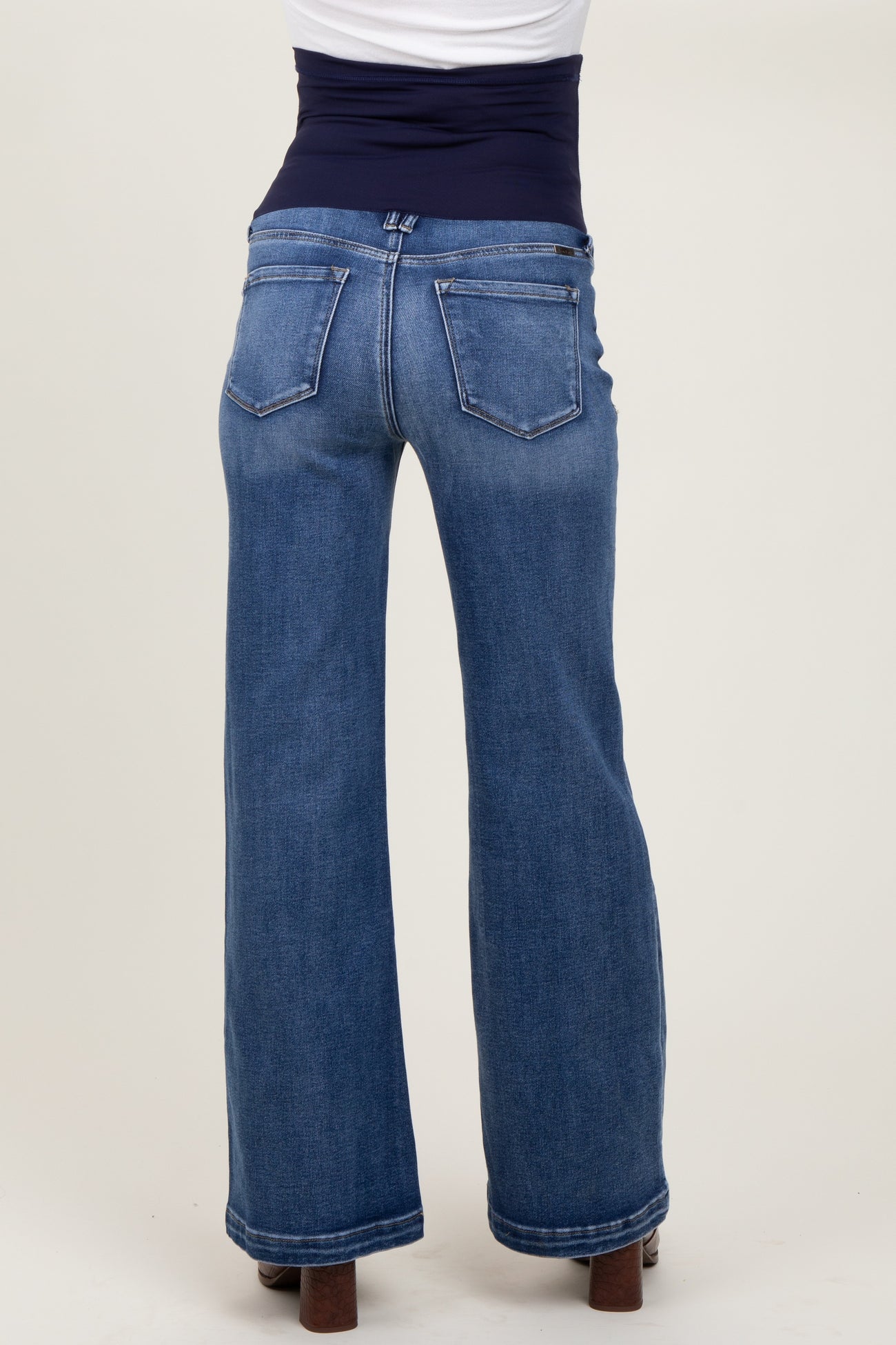 woman wearing dark wash maternity jeans with a wide-leg fit and a supportive waistband, showing the back view