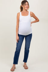 woman wearing a white maternity tank top and blue jeans, highlighting her baby bump