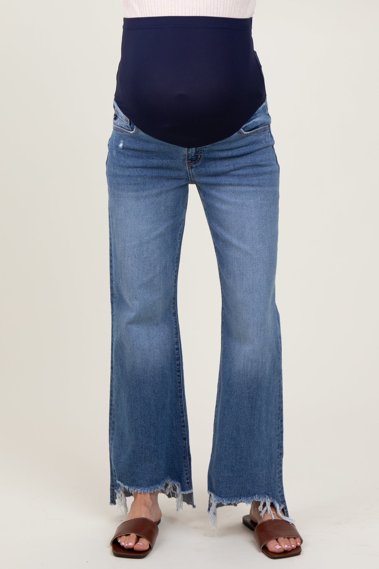 woman wearing blue maternity flared jeans with a navy over-the-bump panel and frayed hems, showing her baby bump