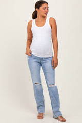 woman wearing a white ribbed maternity tank top and distressed light blue maternity jeans, showing her baby bump
