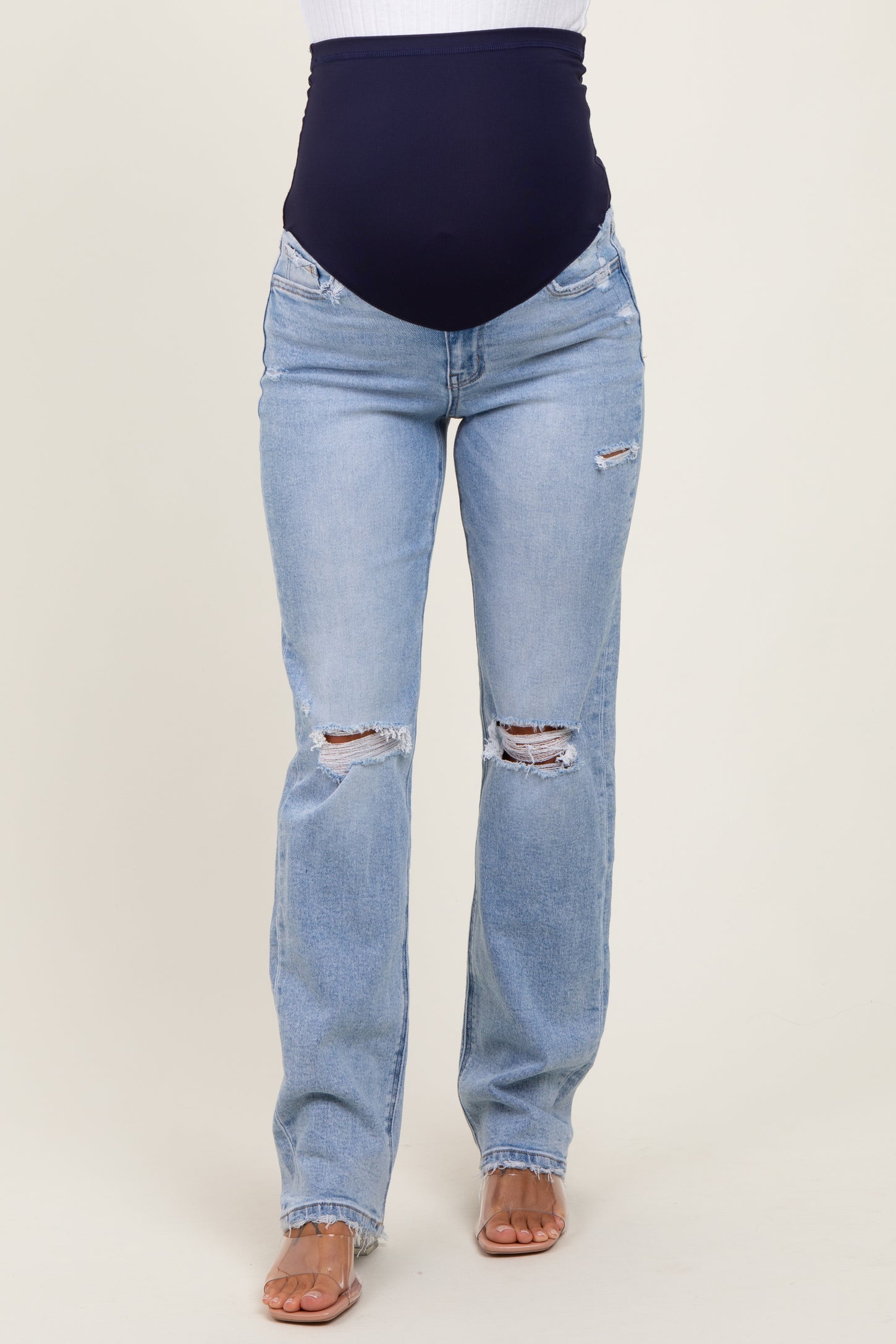 woman wearing light blue distressed maternity jeans with a dark blue over-the-bump waistband