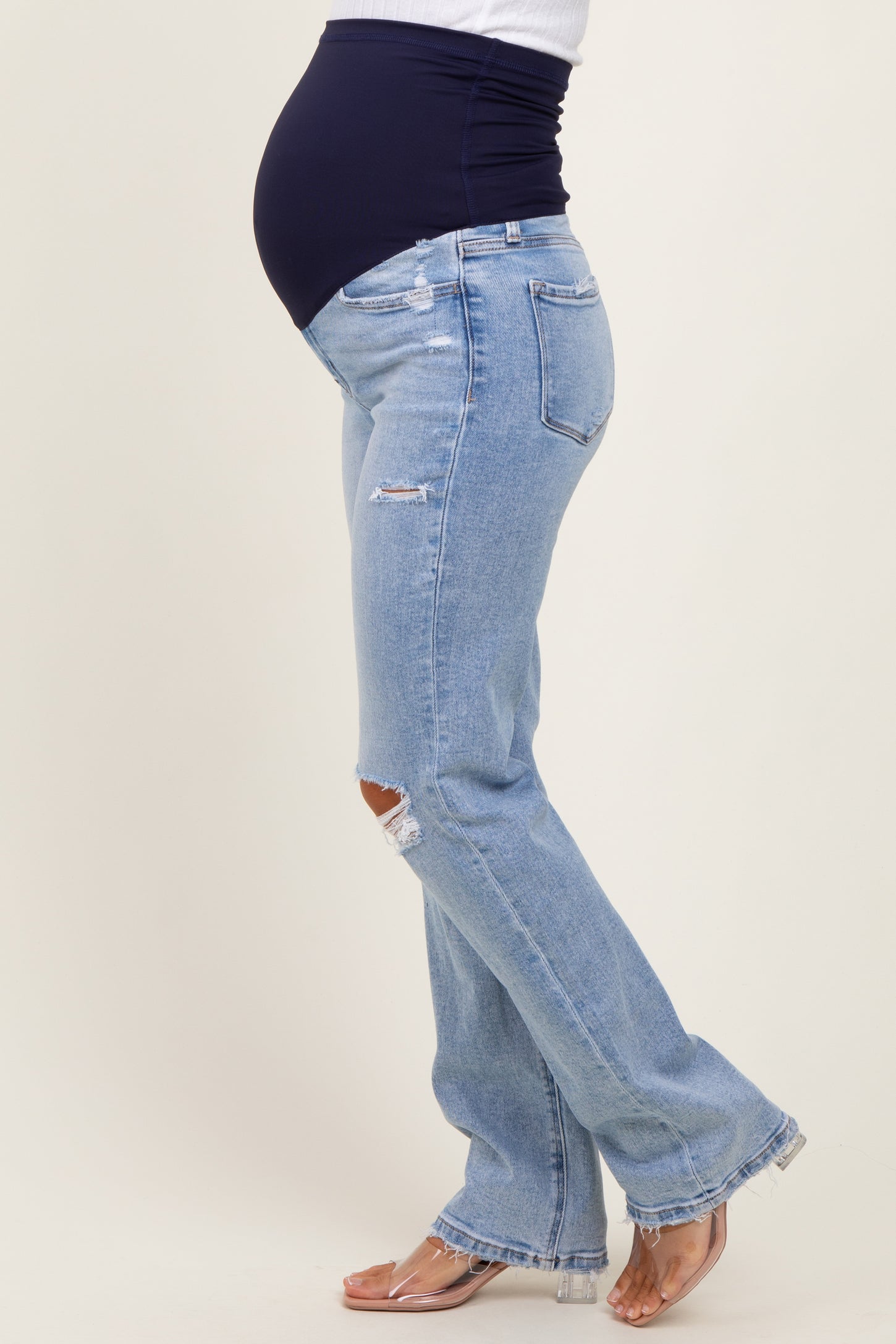 woman wearing light blue ripped maternity jeans with a black belly panel and a visible baby bump