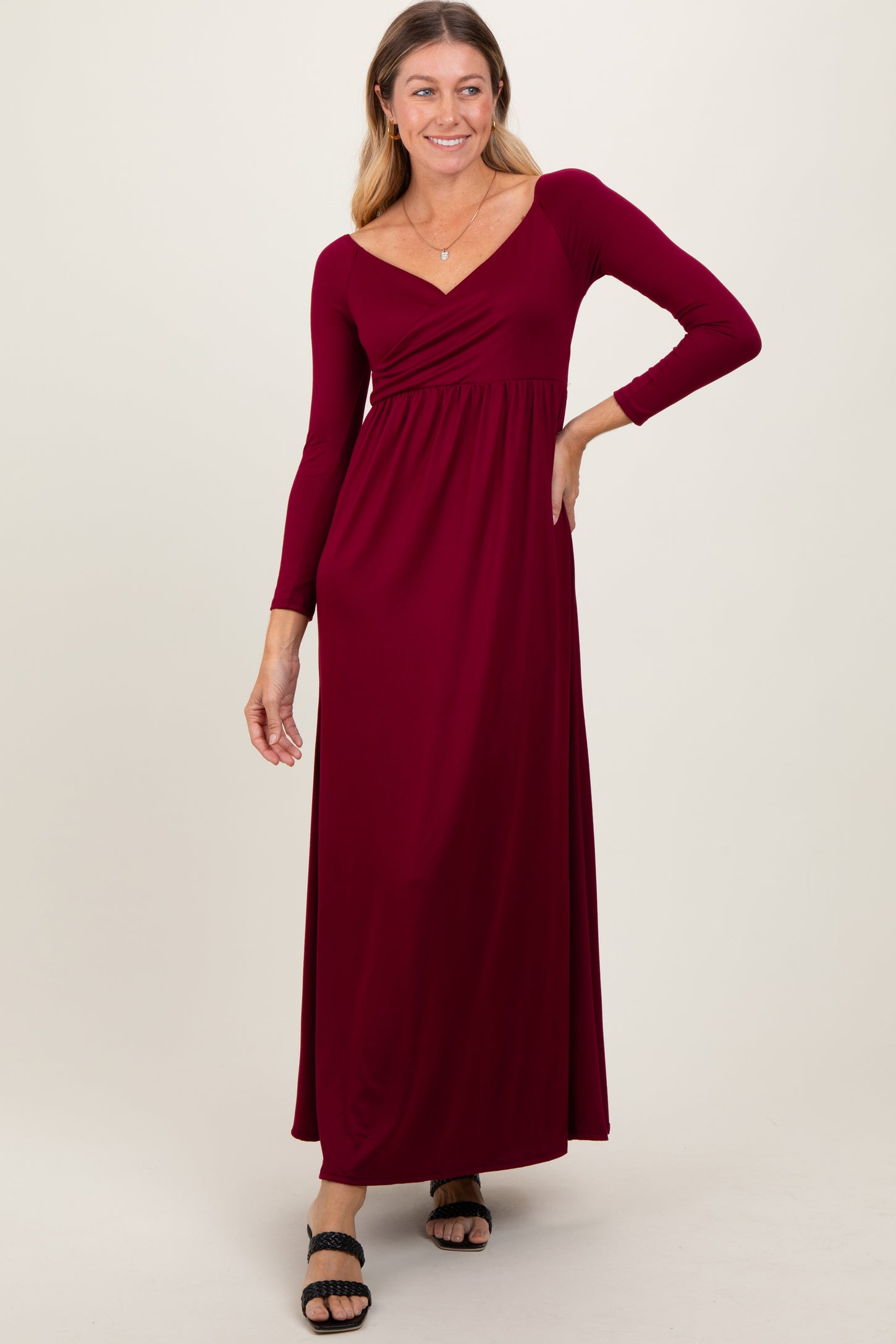 woman wearing a burgundy long sleeve maxi dress with a v-neckline and gathered waist detail