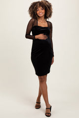 woman wearing a black maternity dress with dotted long sleeves and a fitted silhouette, showing her baby bump