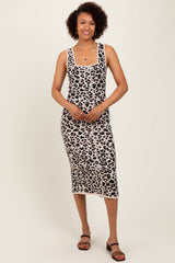 woman wearing a sleeveless leopard print midi dress standing against a neutral background