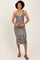 woman wearing a sleeveless leopard print midi dress standing against a neutral background