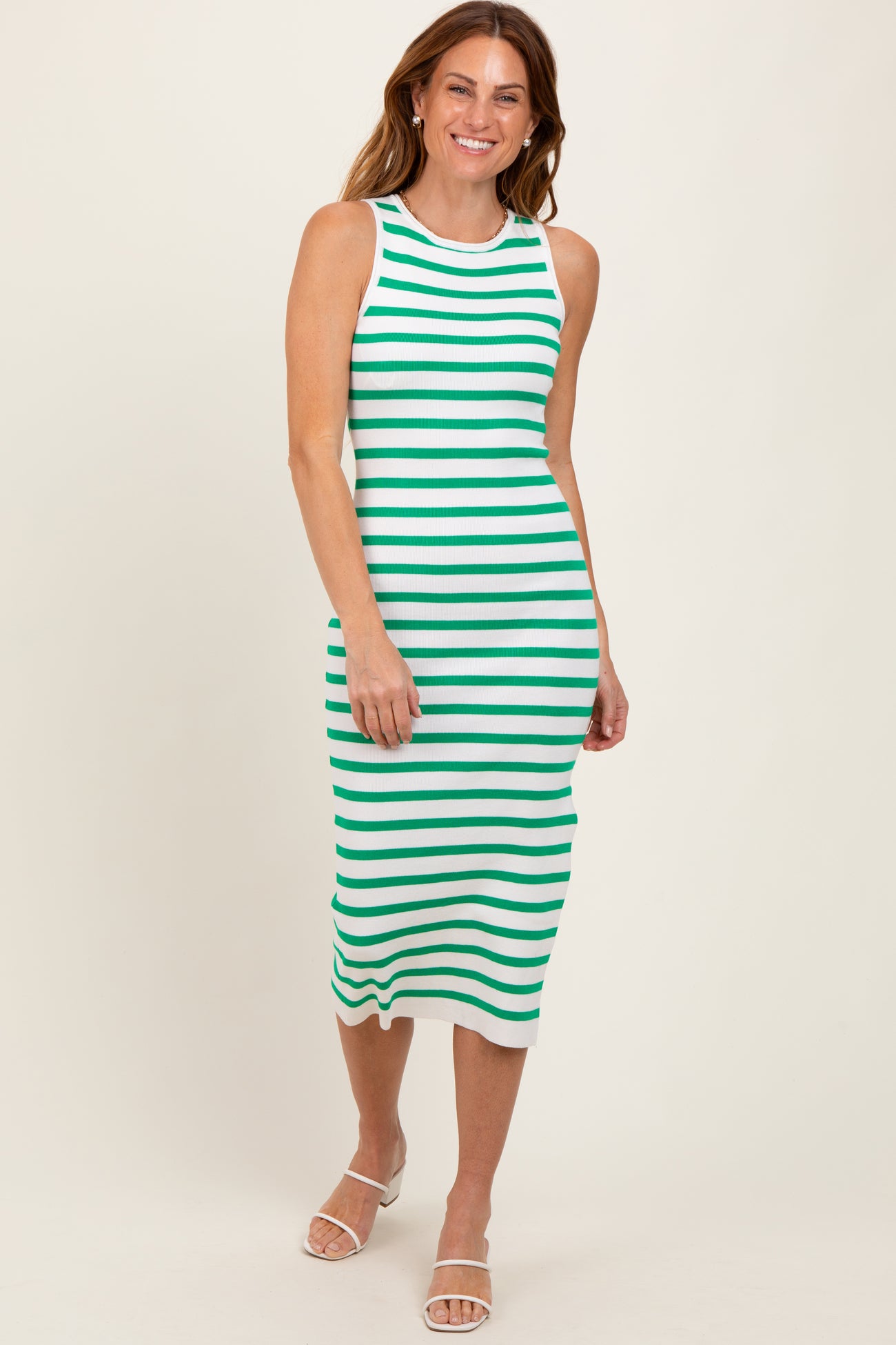 woman wearing a white and green stripe midi dress with a sleeveless design and a fitted silhouette