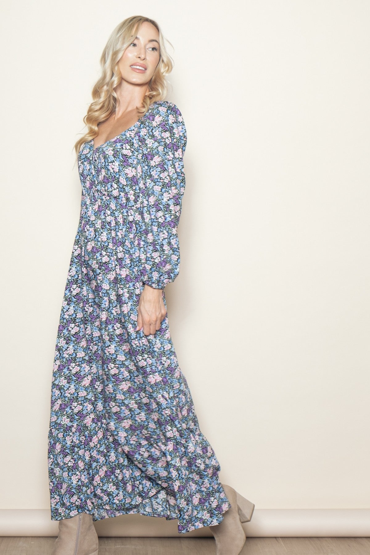 woman wearing a floral maxi dress with puffed sleeves and a square neckline, standing against a light background