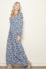 woman wearing a floral maxi dress with puffed sleeves and a square neckline, standing against a light background